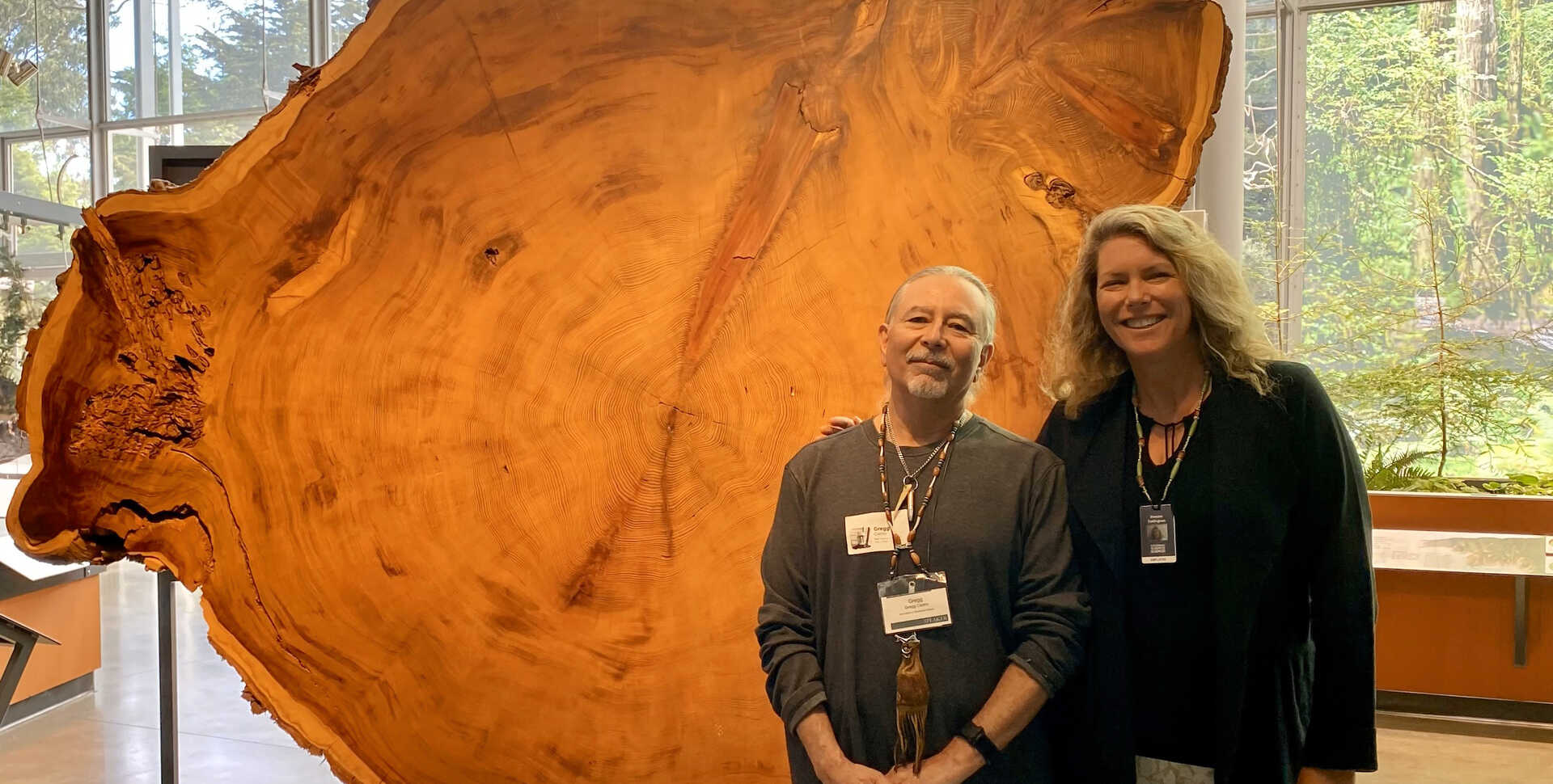 Gregg Castro and Shannon Tushingham pose in front of a redwood round in the Giants of Land and Sea exhibition in Cal Academy. 