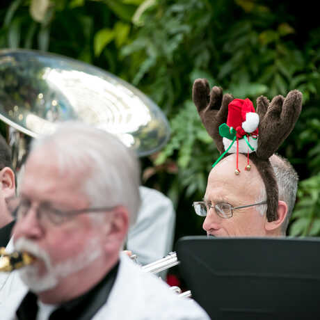Main in reindeer antler headband plays in a brass holiday band in the Academy Piazza