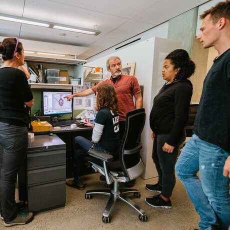 Dr. Brian Fisher points at a computer as Academy entomologists look on