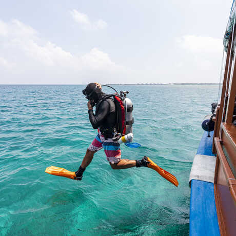 Academy ichthyologist Luiz Rocha in mid-air as he steps off dive boat in the Maldives