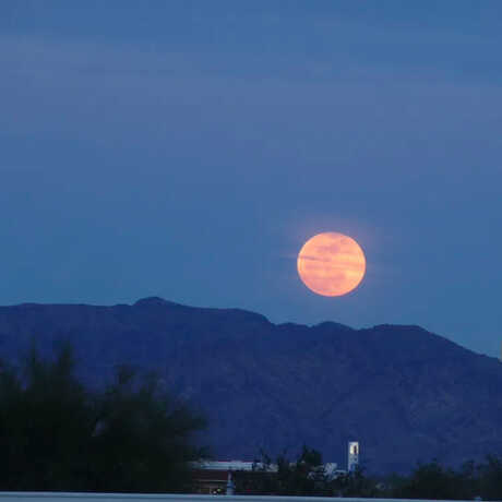 Harvest moon setting over mountains