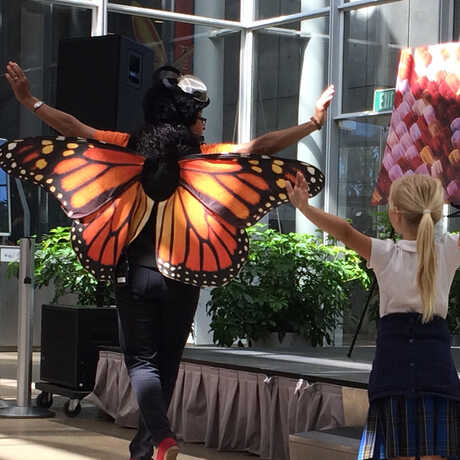 Presenter dressed as a butterfly "flying" with young children