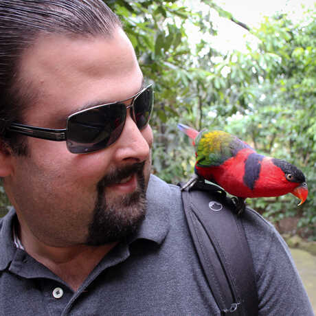 Jason Goldman with a colorful bird on his shoulder