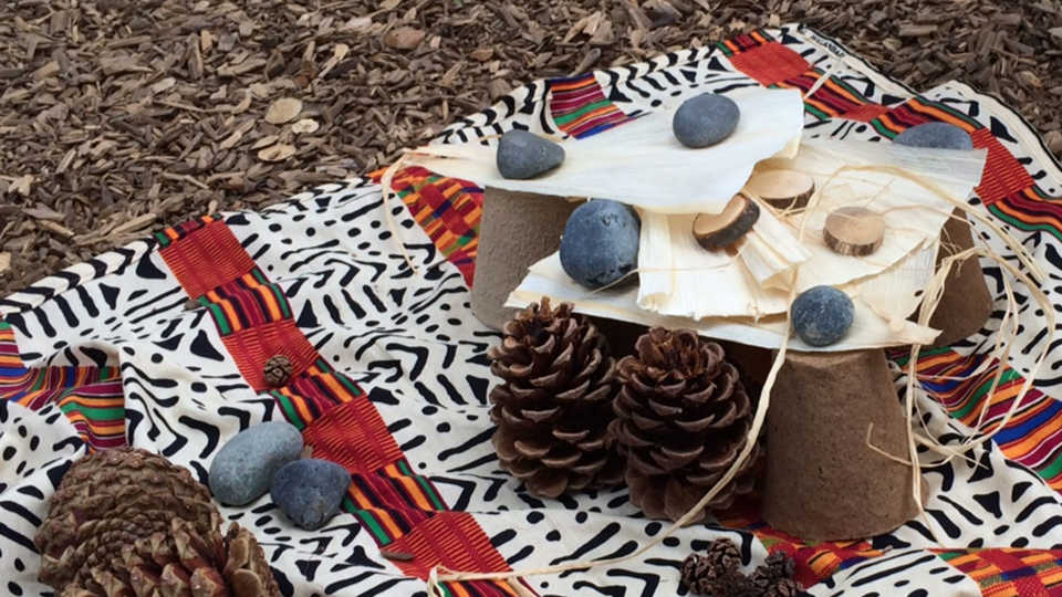 pine cones, rocks, and other natural items on a blanket outside