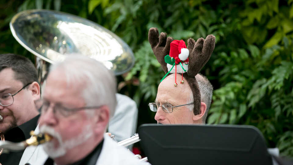 Main in reindeer antler headband plays in a brass holiday band in the Academy Piazza