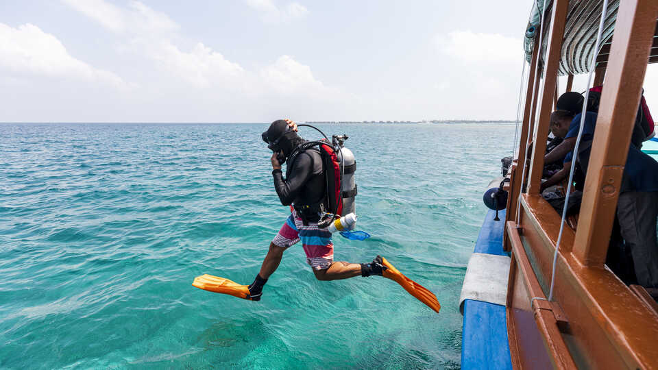 Luiz Rocha steps off a dive boat into the azure waters of the Maldives during an Academy expedition. Photo by Gayle Laird