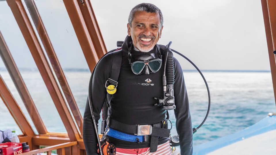 Luiz Rocha smiles on a dive boat in the Maldives during a scientific expedition. Photo by Gayle Laird