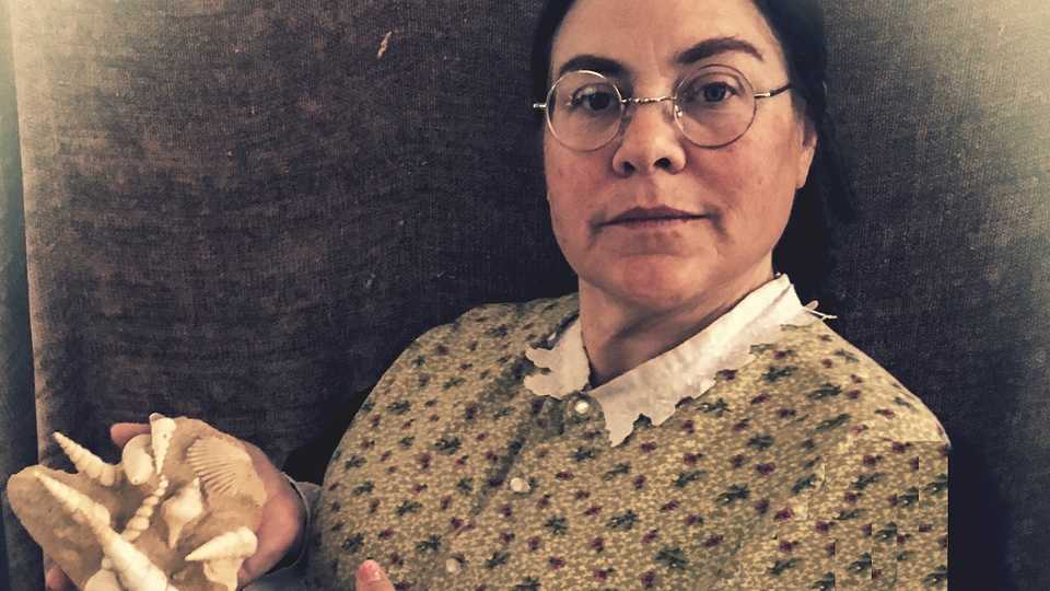 Actress portraying Paleontologist Mary Anning holding fossilized sea shells