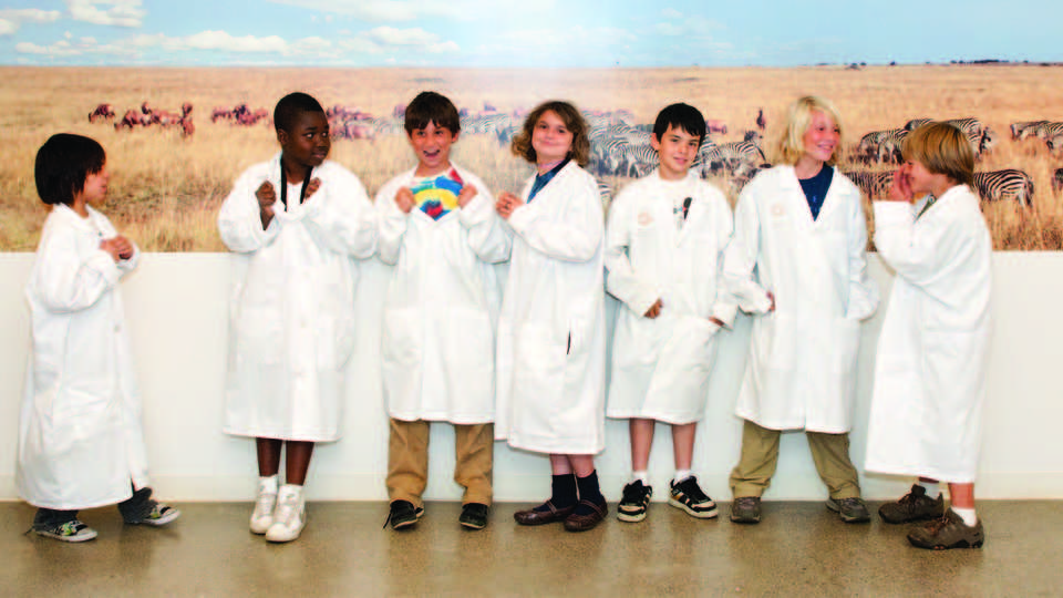 Group of cute kids in white lab coats at the Academy